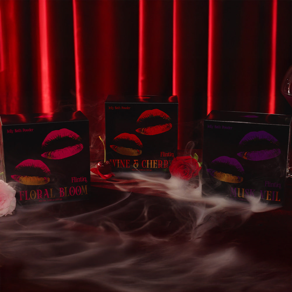 Three boxes with lip design labels on a dark surface with red curtain background