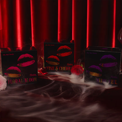 Three boxes with lip design labels on a dark surface with red curtain background